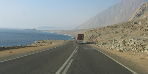 truck on a road near a rocky mountain and sea
